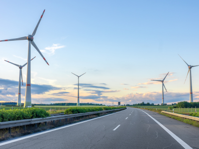 Modern wind turbines spinning on a clear day in a green landscape, symbolizing clean renewable energy.